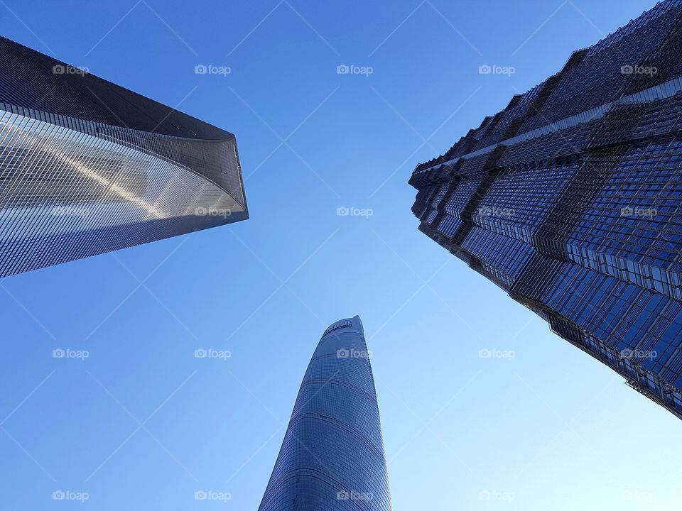 Three of Shanghai's tallest towers, captured together from street level. This shot features Shanghai Tower, Shanghai World Financial Center, and Jin Mao Tower. Taken in May 2018.