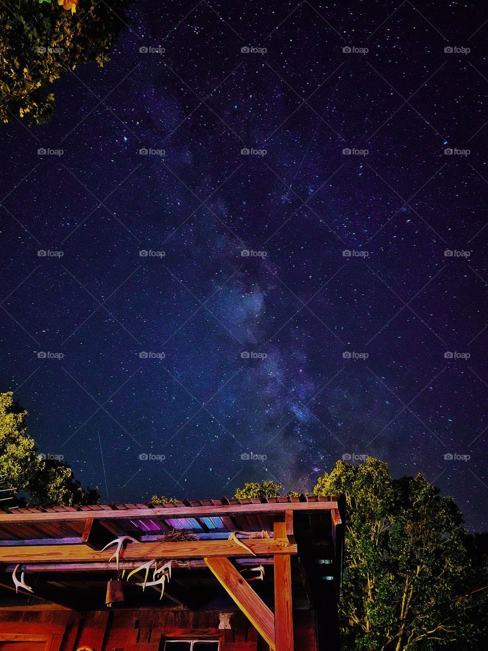 The Milky Way Galaxy rising above a little cabin in the woods bringing nature’s aspects together.