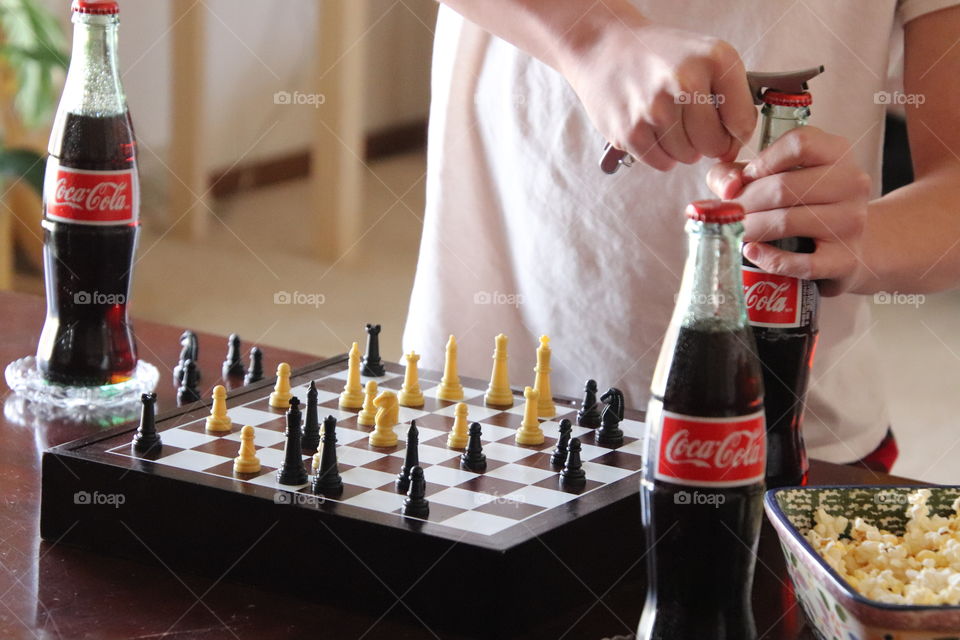 Mom and son playing chess while enjoying Coca Cola and popcorn