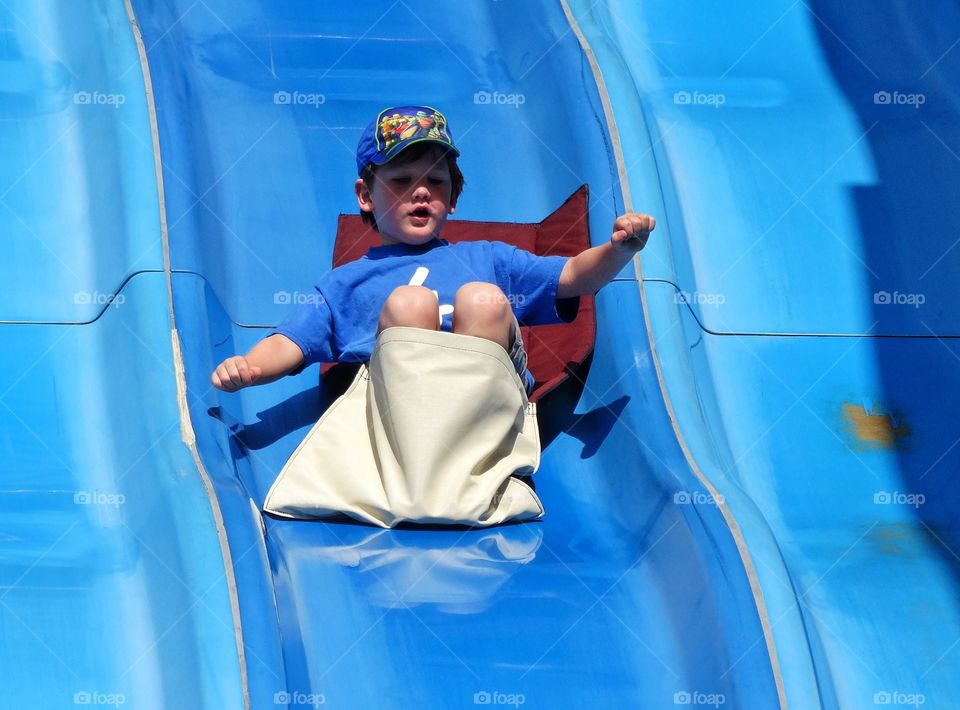 Boy On A Slide. Young Boy Going Down Steep Slide
