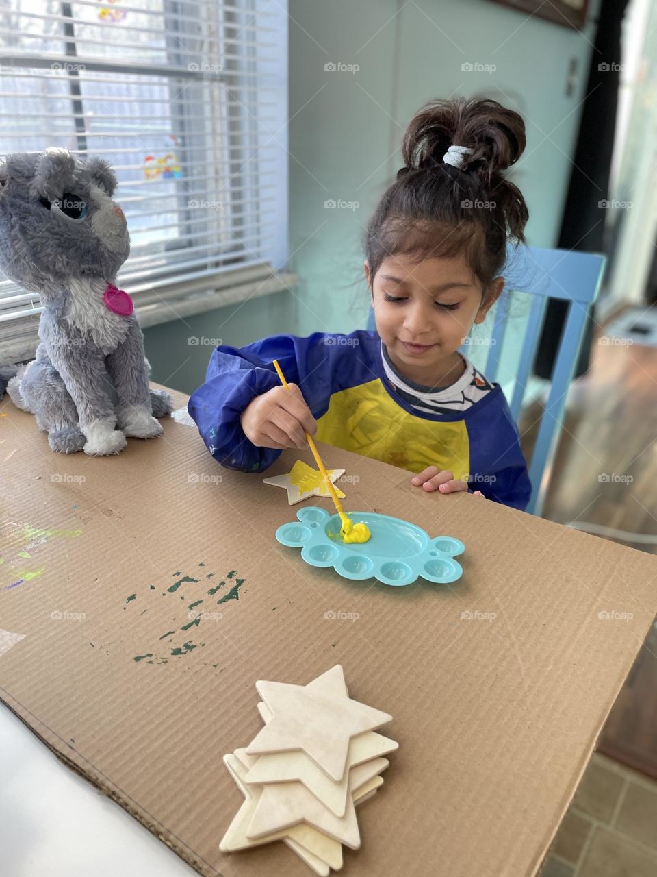 Little girl paints magnets for gifts, making gifts for grandma, crafting gifts for people 