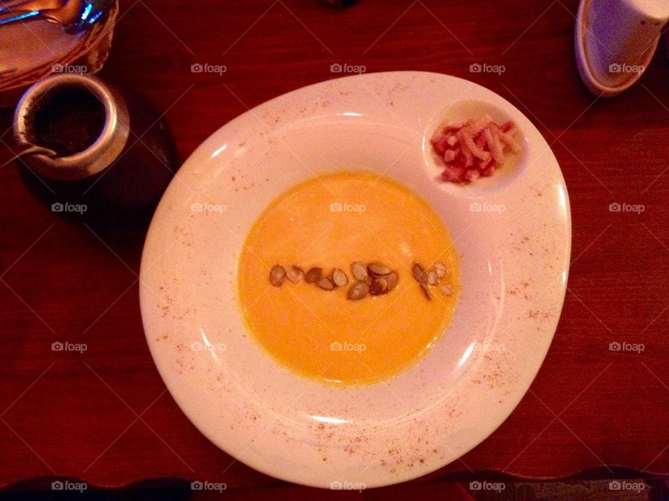 Cream soup of orange color in a plate from above 