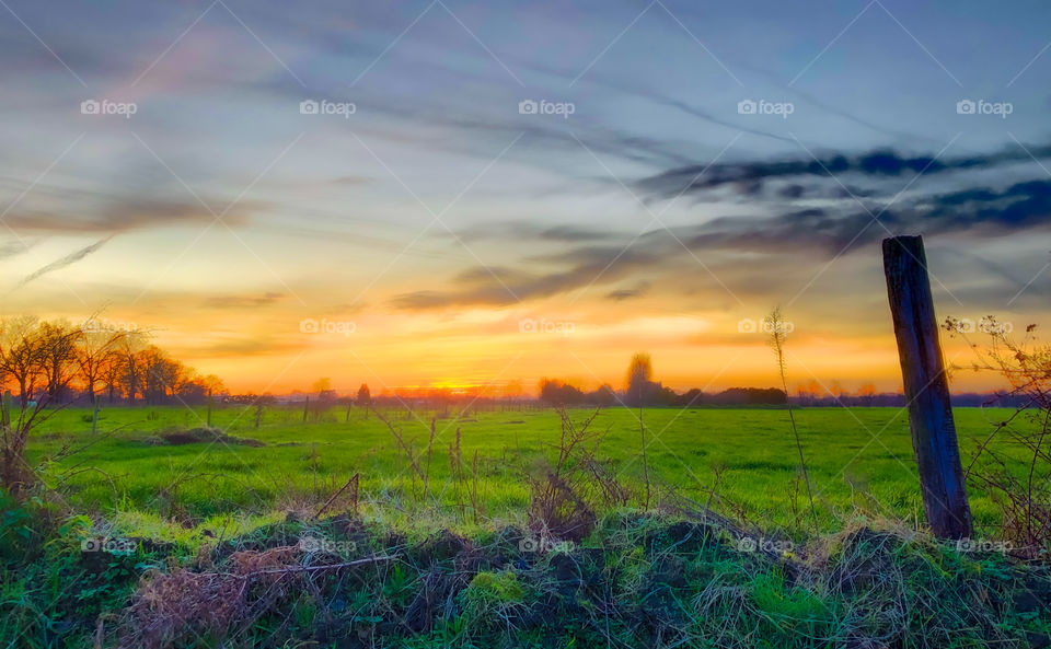 Golden hour dramatic sunset over a grassy Garfield and a barbed wire pole