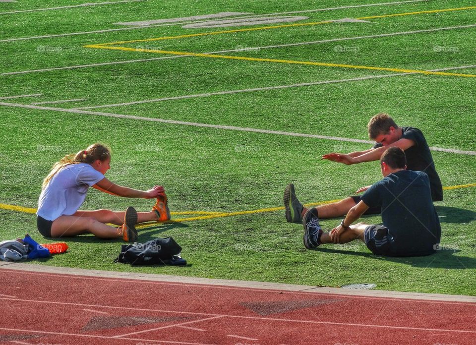 Track And Field Athletes Stretch Before Running. Stretching Before Exercise
