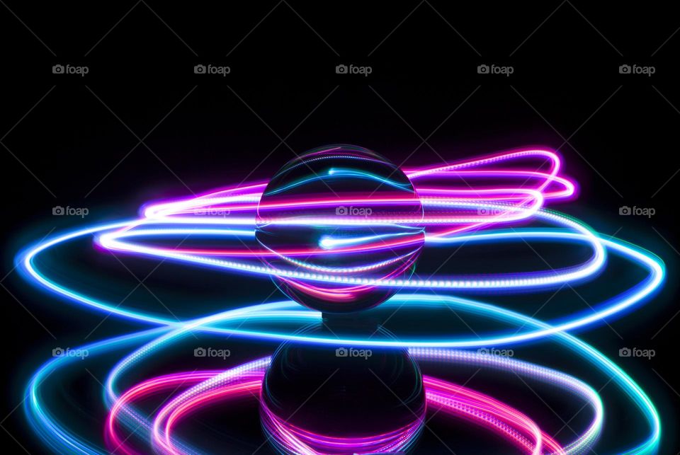 Light painting around a glass ball against a black background