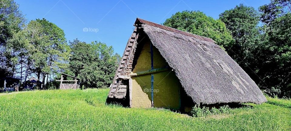 This is a house in the newly created “Keltendorf Gabreta”, a Celtic village built after old models near the township of “Ringelai” in “Bavaria”. The straw covered triangle roof almost reaches the floor in this example. 2023. Hypnotic Productions