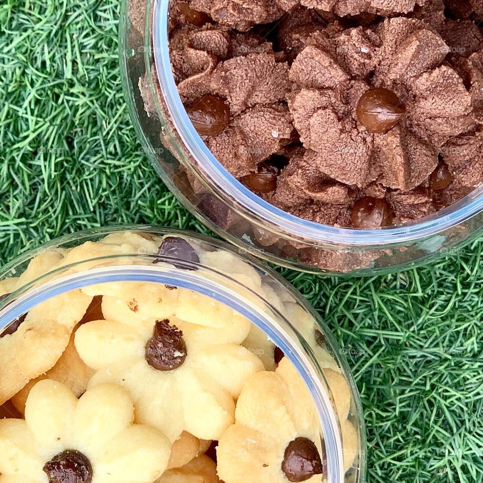 Dark chocolate chips cookies and almond butter cookies in a green nature background , freshly baked 