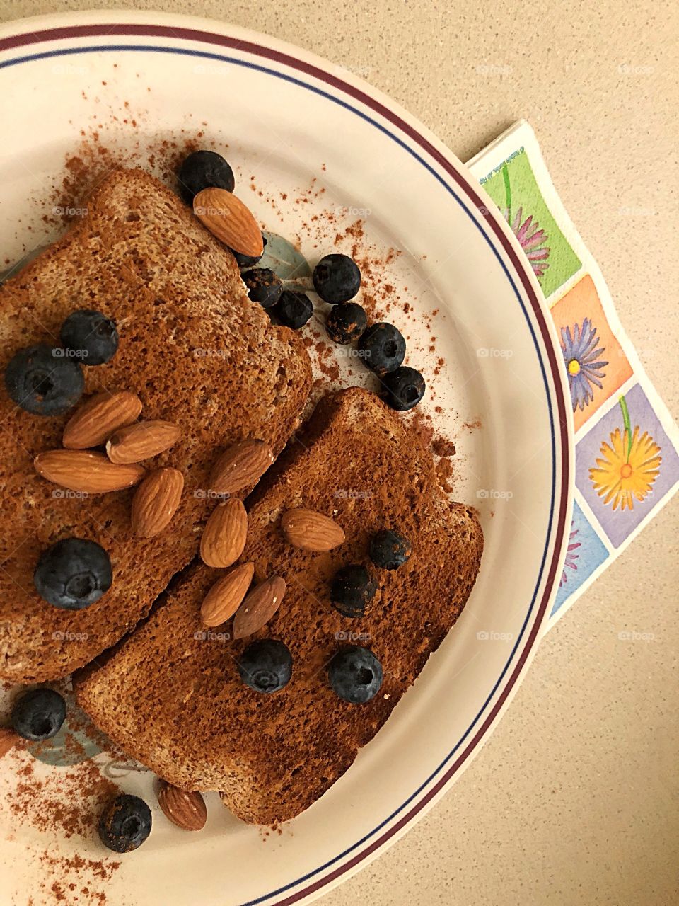 A healthy snack of whole wheat toast , almonds and blueberries. All are sprinkled in Cinnamon.