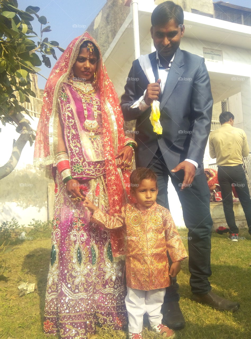 Indian bride and groom standing with child