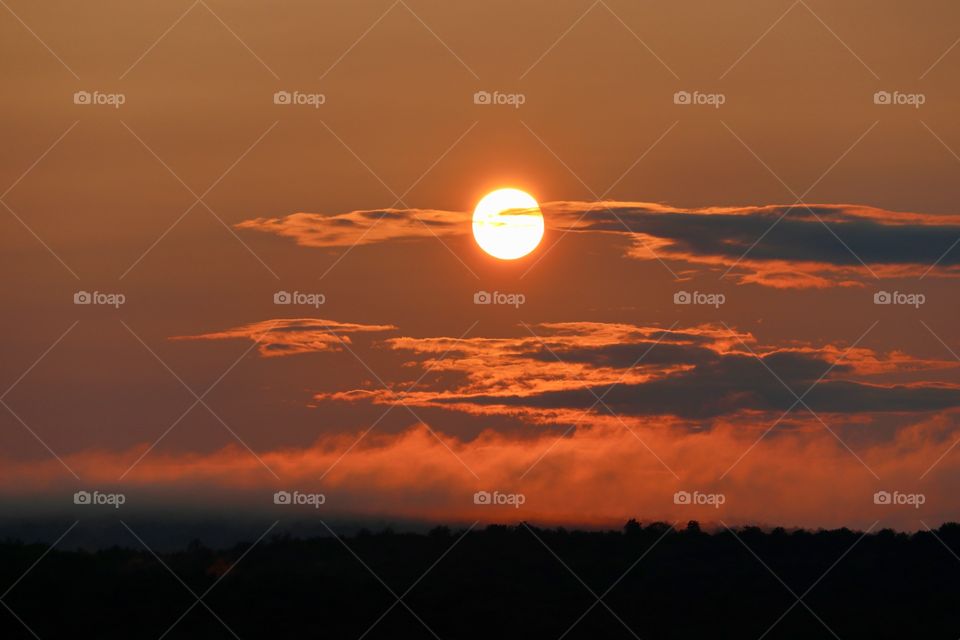 Fiery full sun in sunset over Adirondack mountains and lake