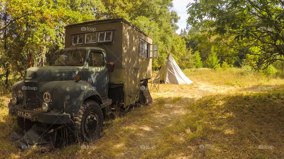 Old German truck converted to a mobile tiny house, with a small tipi tent nearby on a big land