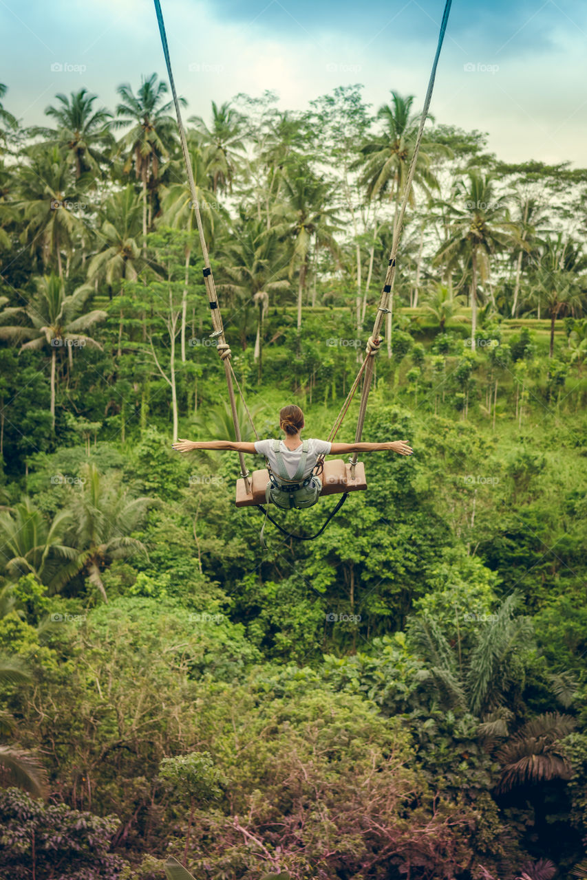 Girl riding on a swing in the jungle.  Bali Island.