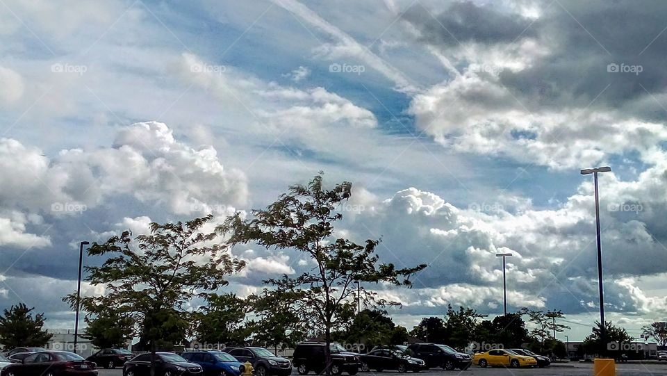 parking lot lined with cars below cloudy sky