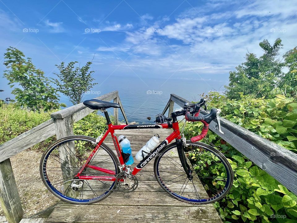 Red road bike at the top of a wooden staircase leading to a beautiful ocean seascape