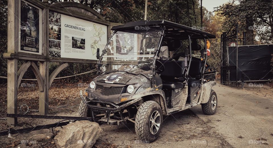 Dark gray vintage dirty electric hunting buggy parked in a private area of ​​a public park in the woods after a hunt, close-up side view. The concept of hunting transport.