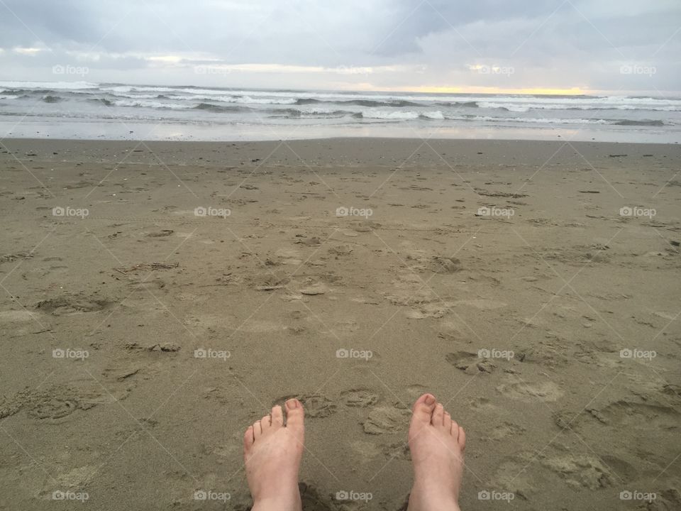 Point of view of the ocean and feet in the sand