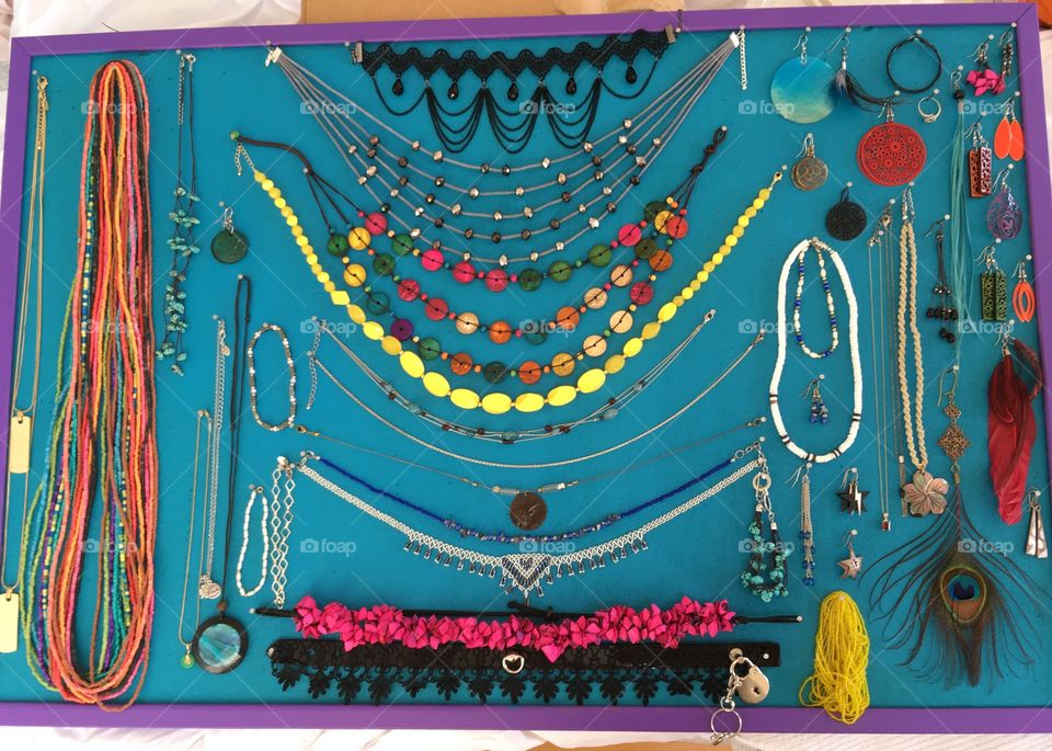 Organized jewelry display on a blue green board with a purple frame 