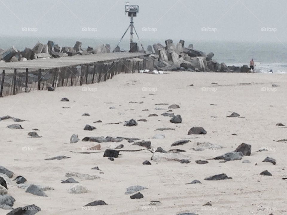 I think of this photo as “moon beach” because to me it resembles the moon with the rocks from the inlet, the grooves in the sand, and the tower on the end of the pier. A sole “explorer” is walking toward the ocean, which gives away its home planet.
