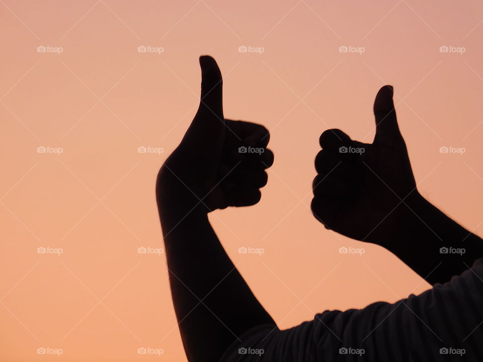 Thumbs-up or All the best silhouette image with sunset light background