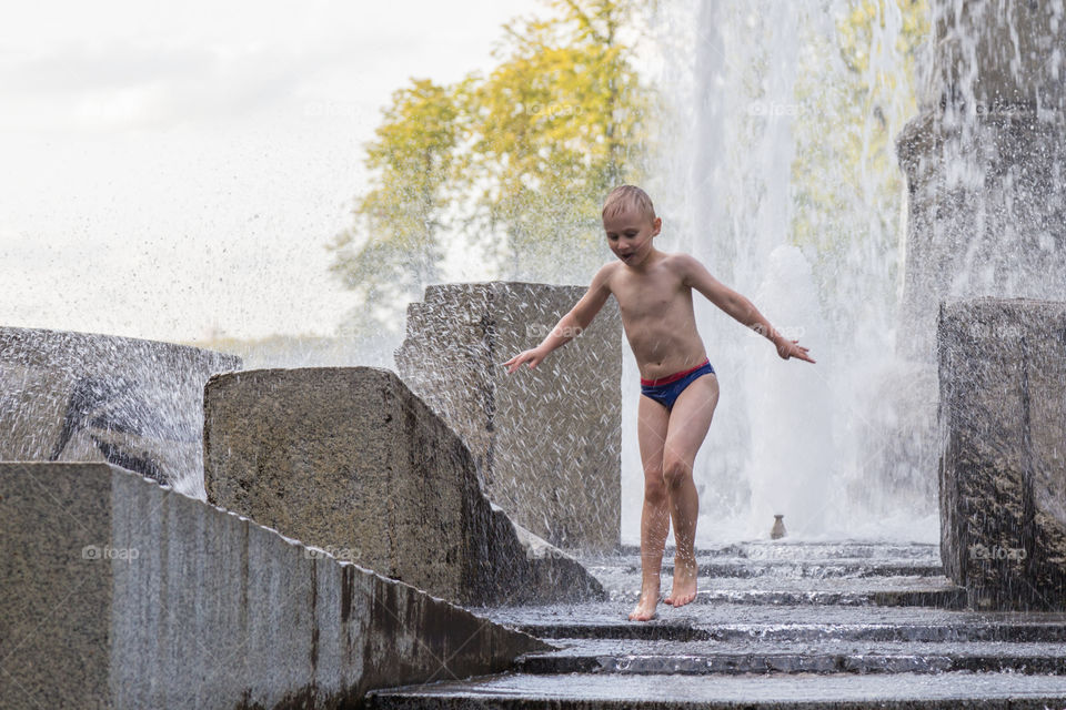 A boy is playing in a fountain