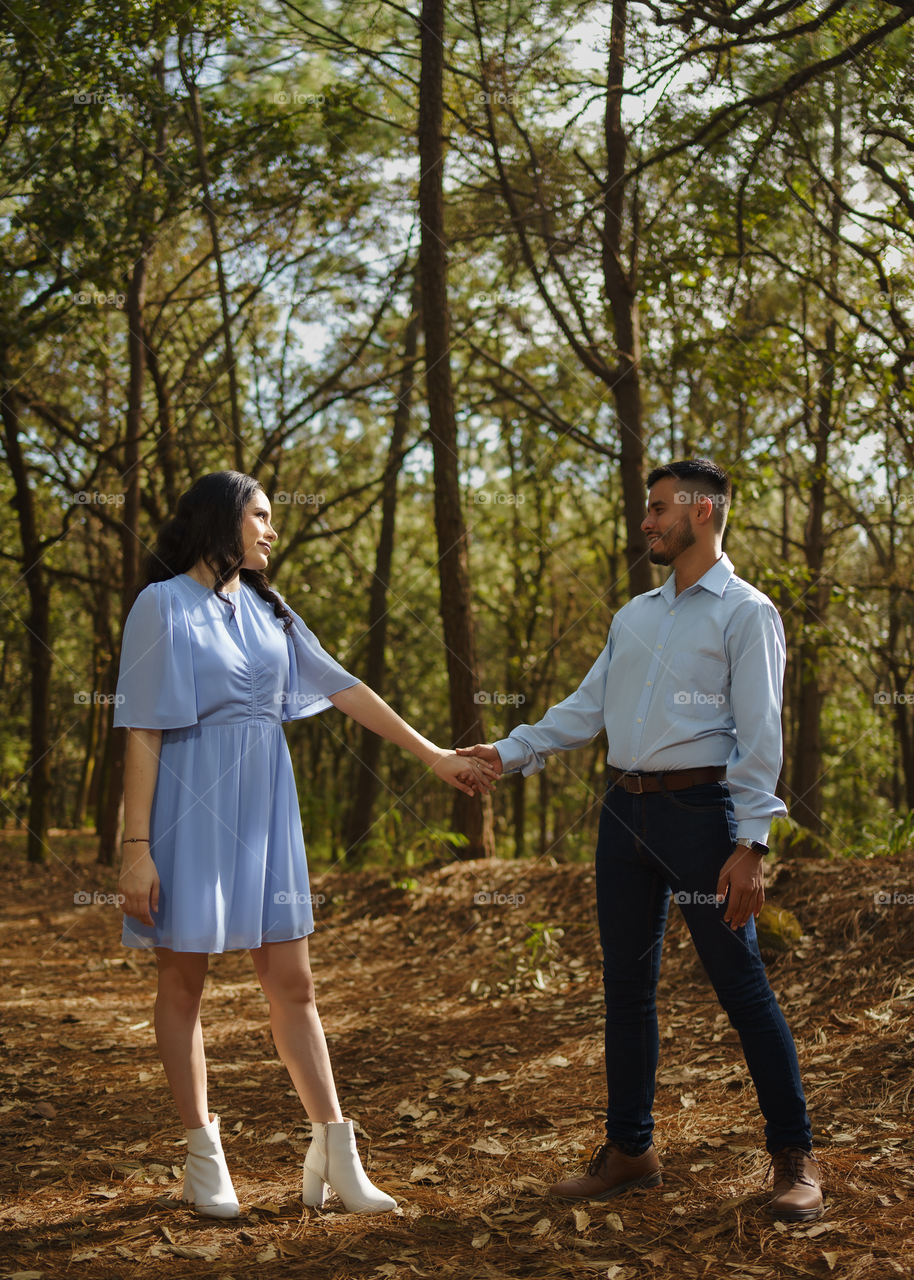 Couples of young people sitting in middle of the forest while looking into their eyes, in a sunny day.