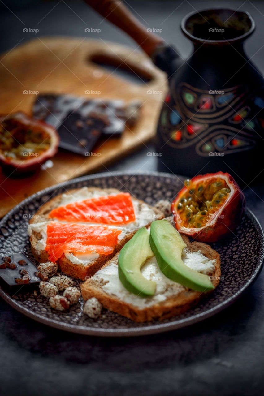 Dietary sandwiches of grain toasts with cream cheese, fish and avocado, and passion fruits 