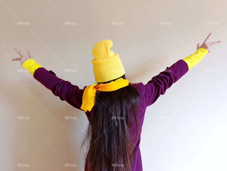 bright image of a girl in a purple coat and a yellow hat.