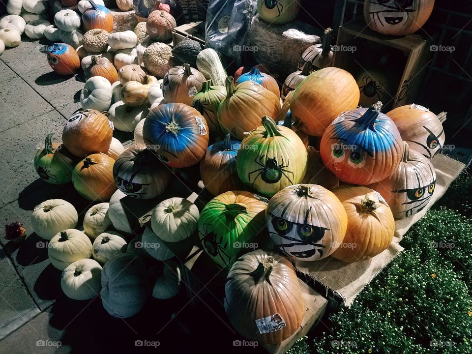Multicolored with differing designs and faces these would be  jack-o-lanterns sit and wait for their Halloween debut.