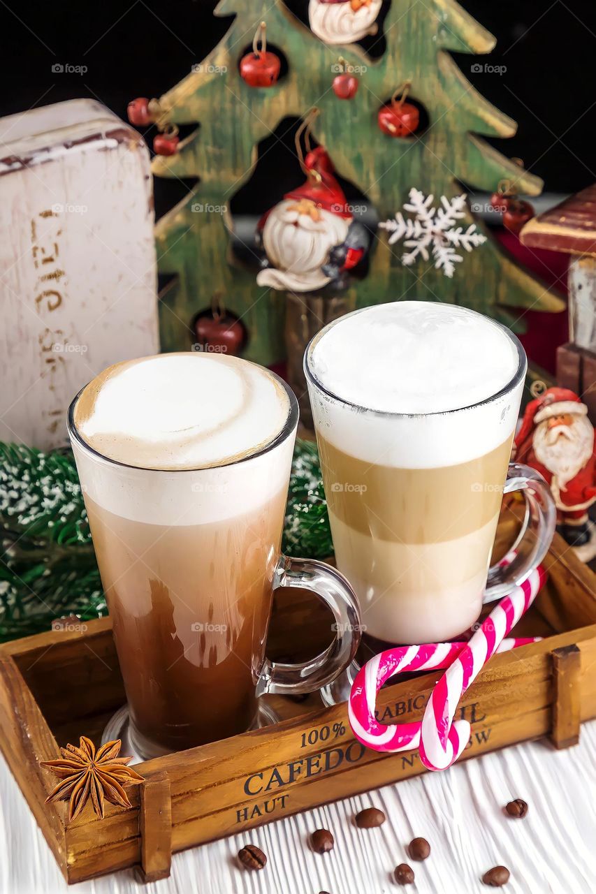 Close up of frothy, layered cappuccino in a clear glass mugs
Close up of frothy, layered cappuccino in a clear glass mugs surrounded with star anise and coffee beans.