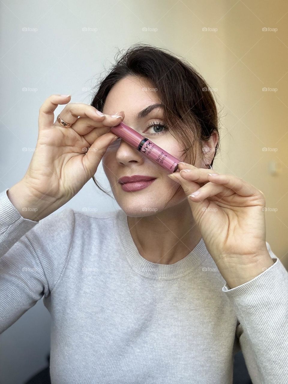 Woman’s portrait with product, girl holding a lipstick in her hands 