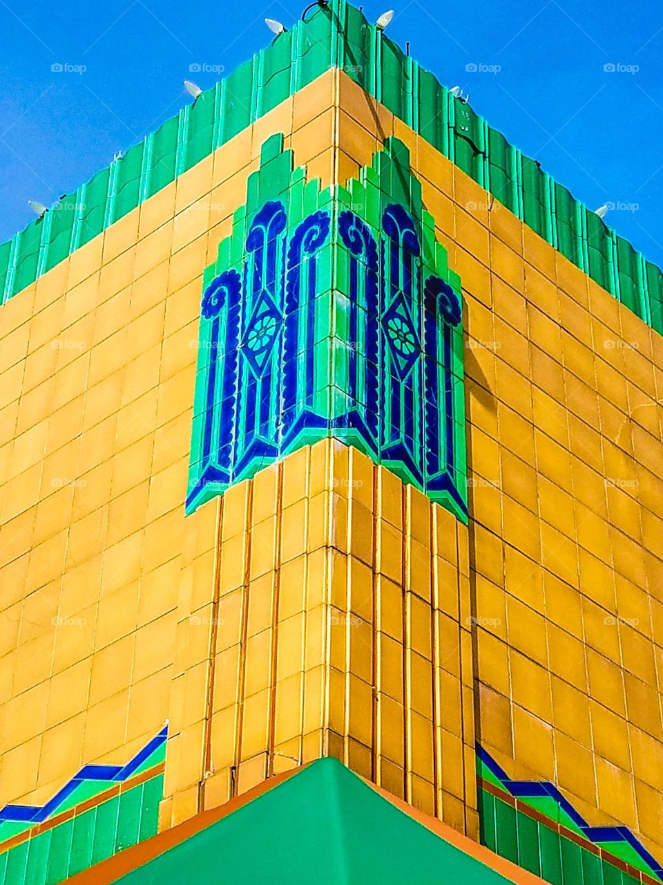 Corner shot of an art deco building with yellow, turquoise, blue tiles, vibrant colors 