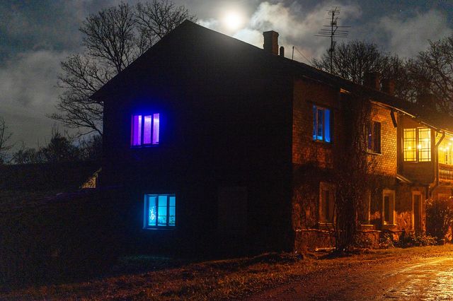 Blue, purple and warm yellow light in the windows of the house at night
