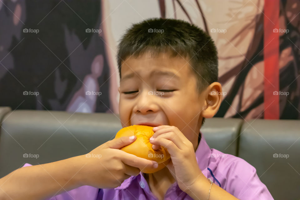 Hamburger fish in hand asia boy holding the eating.