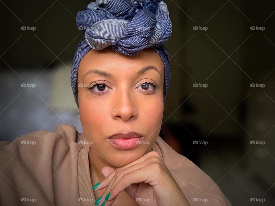 A self portrait of a woman wearing makeup and a head wrap.