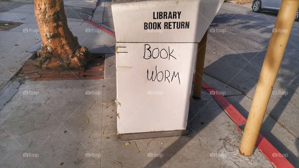 An old library book return box with the words "book worm" on it.
