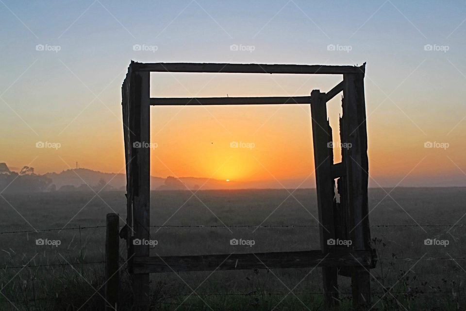 Sunrise framed through  old timber shed in rural field