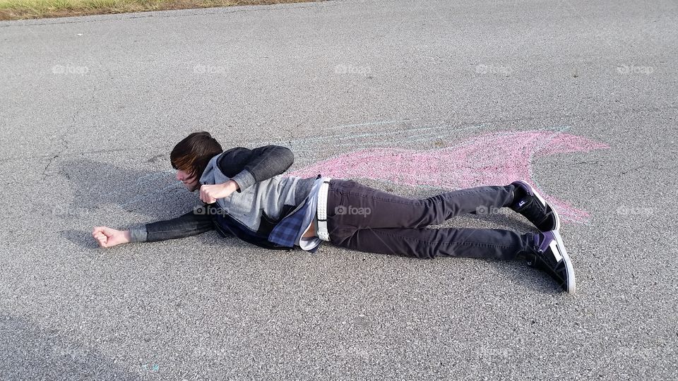 Man lying near snake drawn with chalk on street