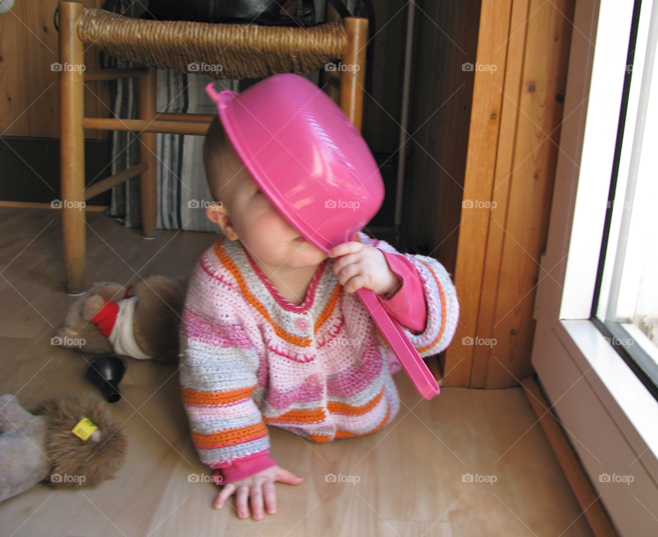 Happy baby girl plays with a pot