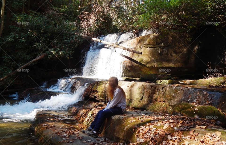 girl setting on large rock admiring upper Crow creek waterfall
