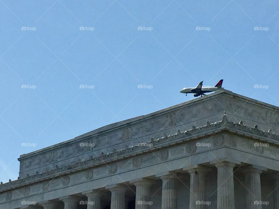 An Airplane flying passing on top of Lincoln Memorial Building of Washington DC