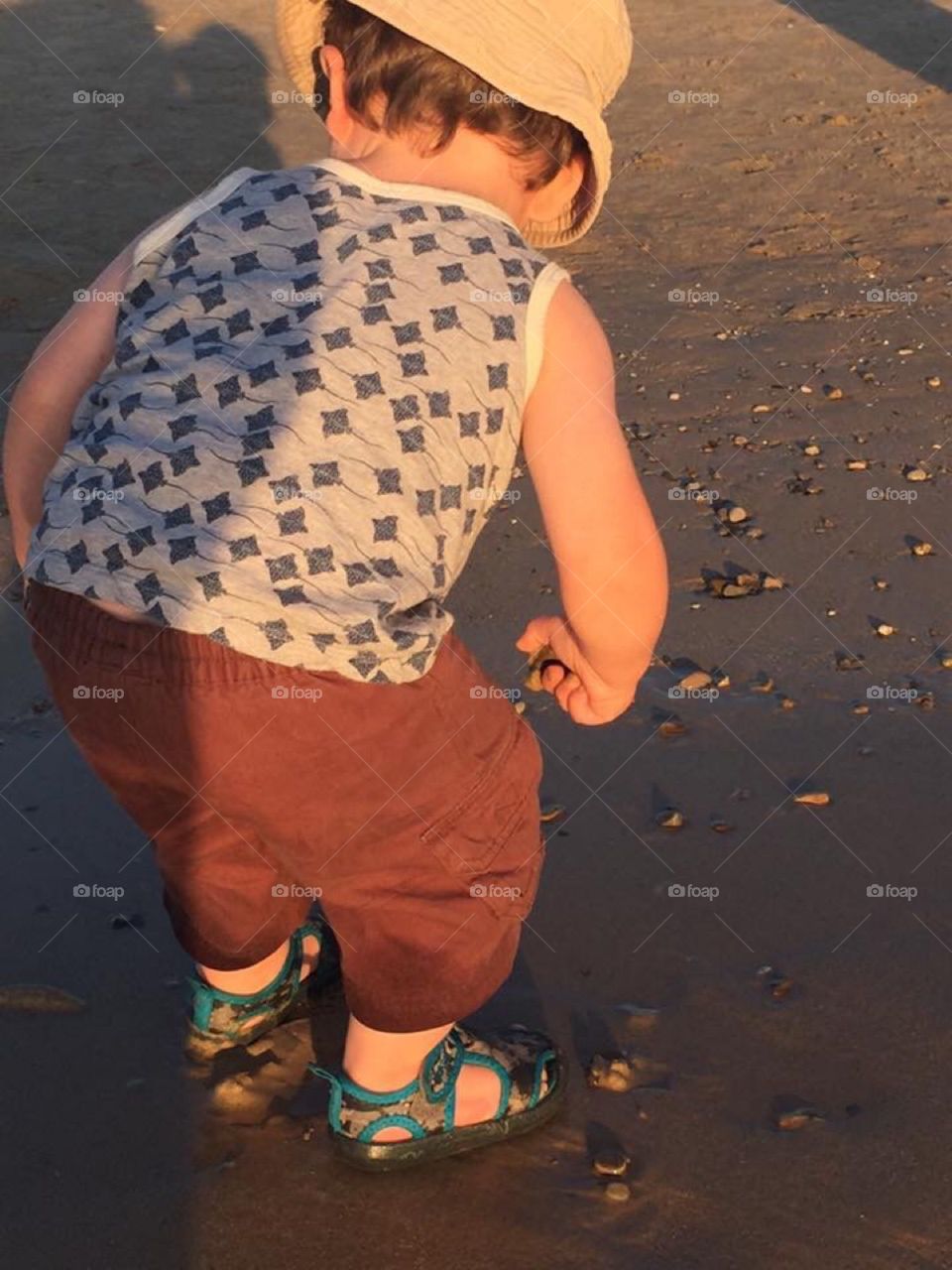 Toddler Picking Up Pebbles on the Beach