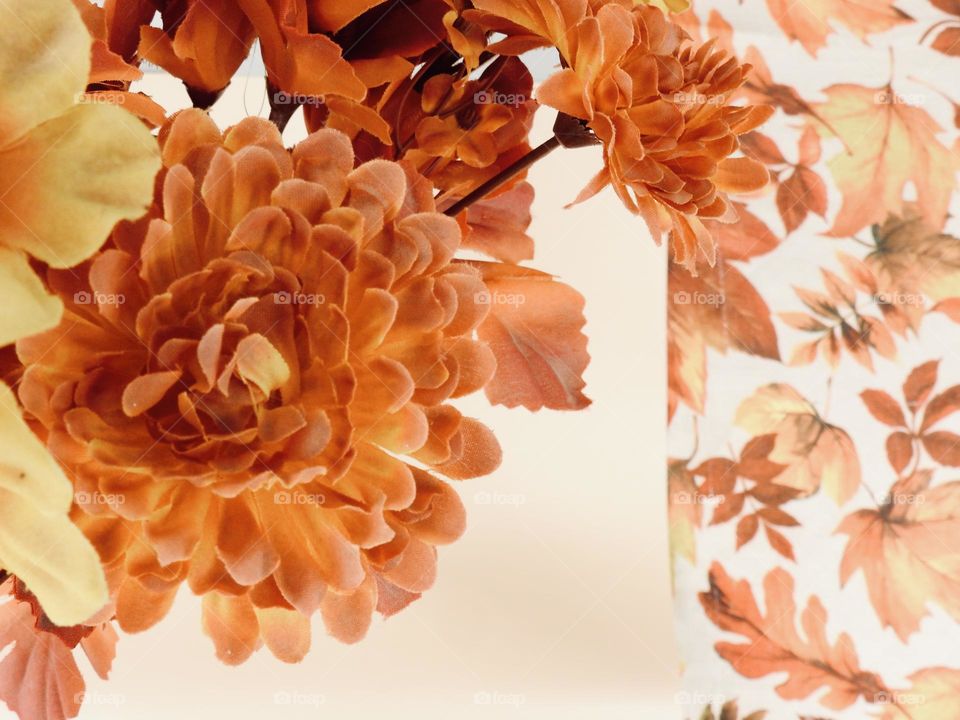 Orange yellow bouquet representing fall autumn on top of a beige background and cloth with orange leaves drawing.