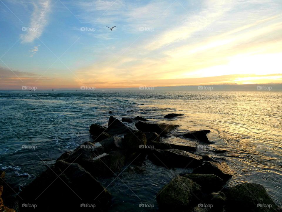 A summertime sunrise off the jetty over the ocean with subtle hues