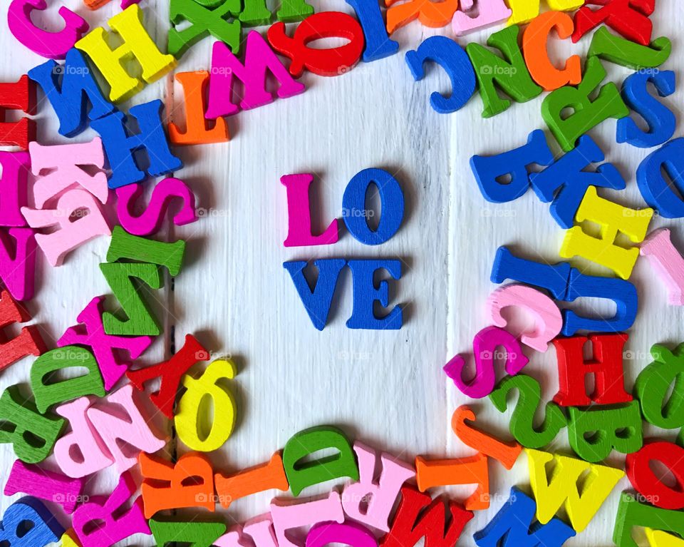 wooden letters of the English alphabet on a white wooden surface, the word love