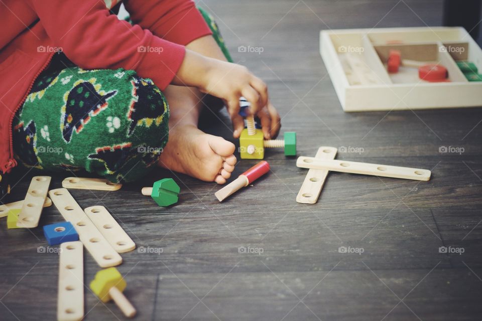 Kid learning use of screws and bolts practically using wooden samples and trying to make creative structures using the same. Learning and fun both at same time