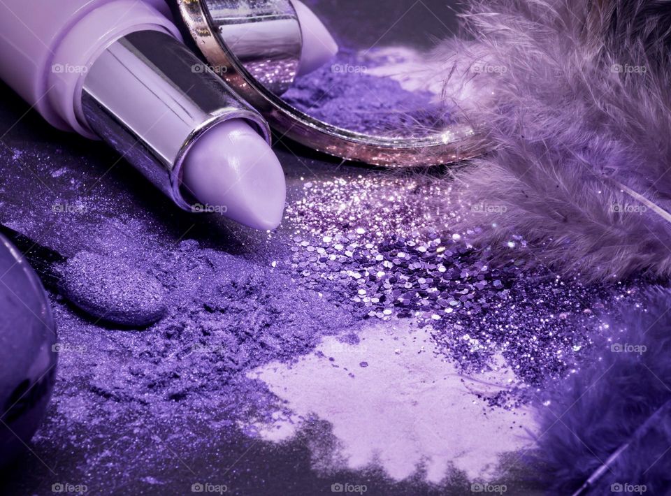 Overdose on purple sparkle and glitz - assorted purple powders and glitter with lipstick, mirror and feathers