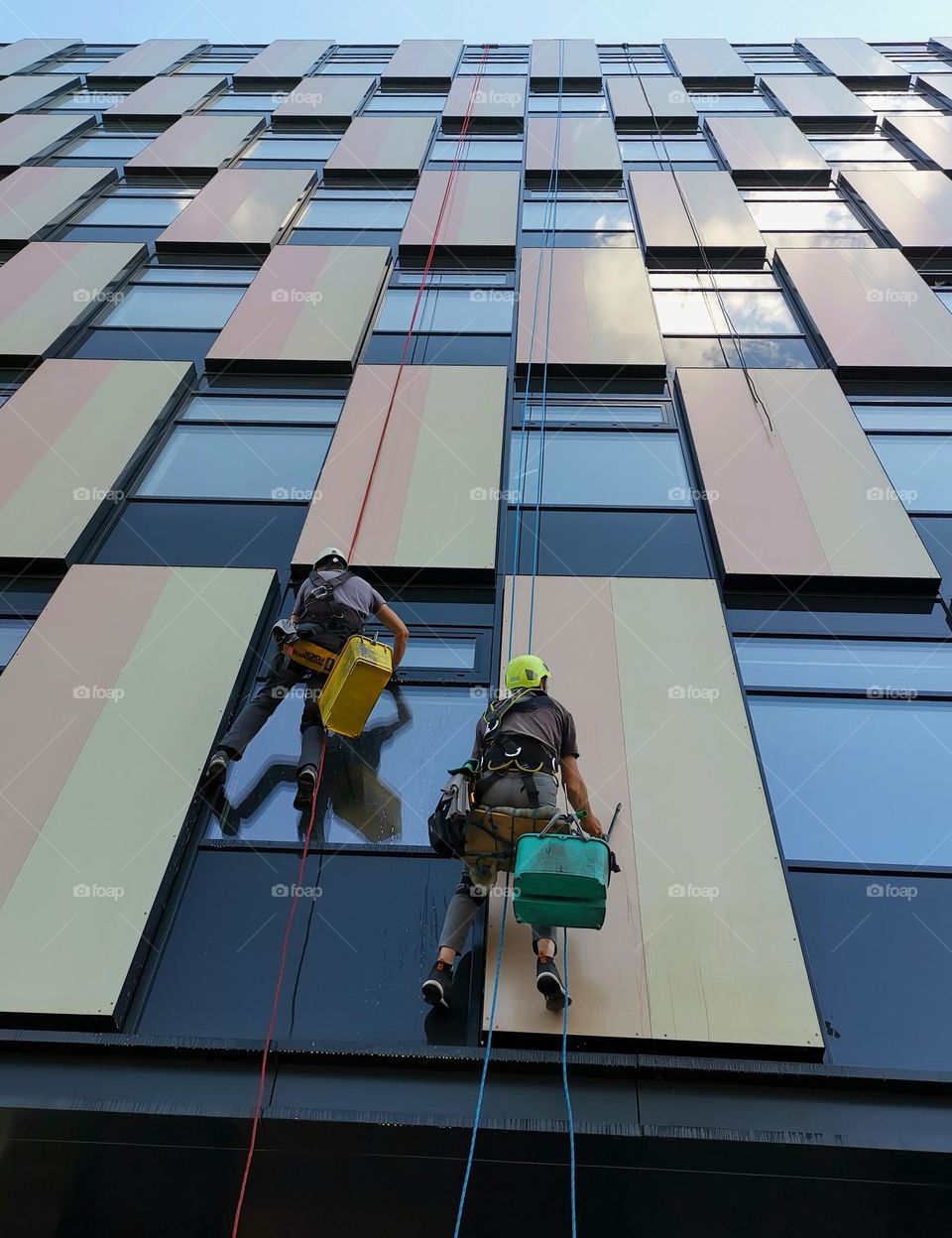 From the ground up. Two window cleaners clean windows in a multi-storey building. Skyscrapers. Street photo.