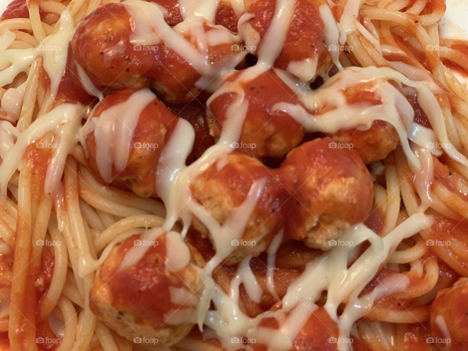 The meatball and pasta dinner with shreds of melted mozzarella cheese on them that I made.