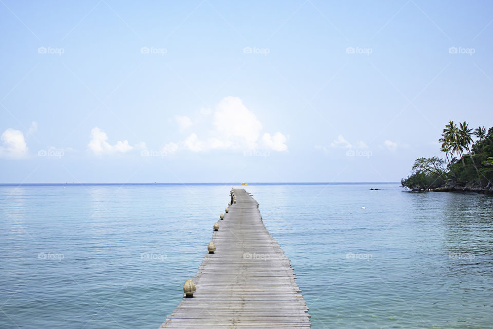 Wooden bridge pier boat in the sea and the bright sky.