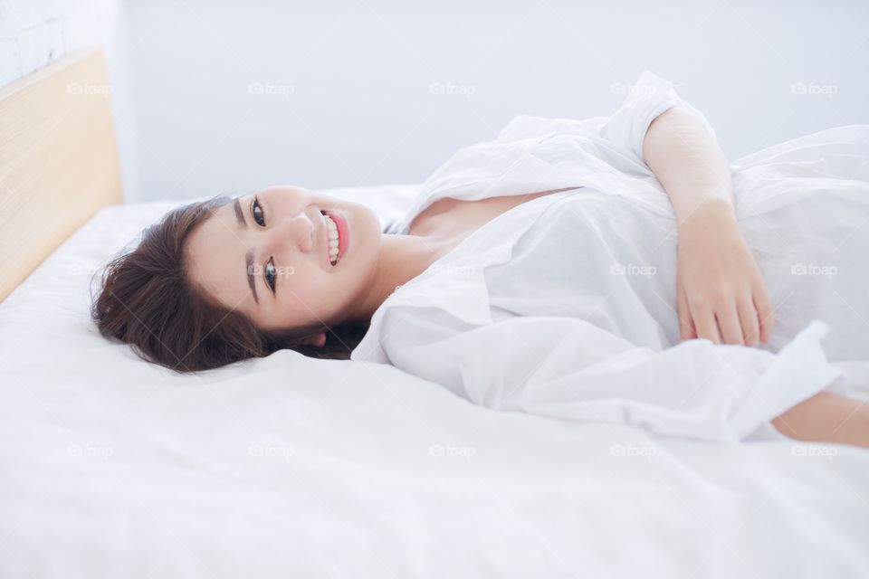 Beautiful sexy Asian woman smile on bed and looking at camera 